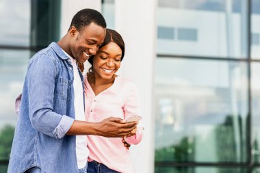 New Country 'ye geldikten sonra internet üzerinden otel rezervasyonu yapan neşeli siyah çift, havaalanı binasının yanında duran romantik Afro-Amerikan eşler, İnternet' te konaklama rezervasyonu yapıyorlar.