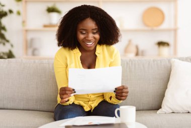 Mutlu siyah kız öğrenci ya da çalışan kağıttan iyi haberler okuduğu için heyecanlı, büyük anlaşma, pozitif sınav sonucu.