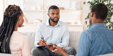 Siyahi eşlerle seans yapan, sorunlarını dinleyen ve not alan, Afro-Amerikan Psikolog, Ofisinde Çifte Danışmanlık yapan, Seçici Odaklanan