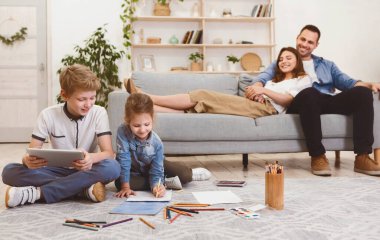 Aile Hafta Sonu. Mutlu ebeveynler, çocuklar evde yerde otururken dinleniyor. Seçici Odaklanma