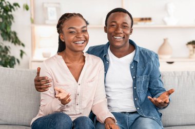 Uzlaşma bulundu. Başarılı bir terapiden sonra danışmanlık koltuğunda mutlu siyah çift pozu, kameraya gülümseme, boş alan.