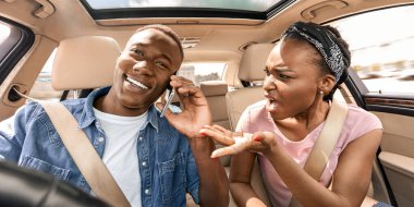 Duygusal siyahi kadın erkek arkadaşına bağırıyor araba kullanırken telefonla konuşuyor, kapatıyor. Kızgın afro-amerikalı kadın şoförün yanında oturuyor, akıllı telefondan konuşuyor, bağırıyor ve el kol hareketi yapıyor.