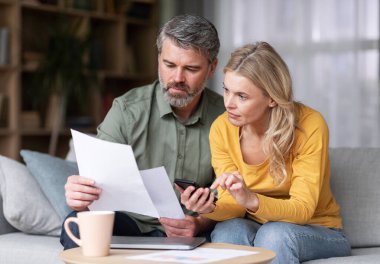 Evli, orta yaşlı bir çift, birlikte planlama bütçesi, gazete okuyor, oturma odasında koltukta otururken, karı koca, evrakları kontrol ediyor, vergi hesaplarını kapatıyor...