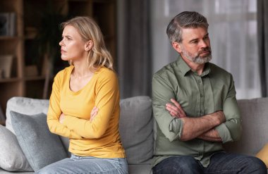 Crisis In Relations. Middle Aged Husband And Wife Offending To Each Other After Argue, Grumpy Spouses Sitting On Couch With Folded Arms, Married Couple Angry After Domestic Quarrel, Free Space