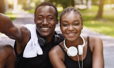 Açık hava eğitiminden sonra fotoğraf çektirmek için poz veren neşeli siyah çiftin kendi portreleri. Kameraya samimi bir şekilde gülümsüyorlar.