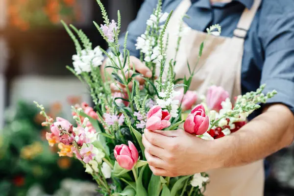 Tasarımcı bitkilerle çalışıyor, modern kompozisyon. Çiçekçi dükkanı ve küçük işletme. Önlüklü genç adam müşteri için metal kovada çiçek stüdyosunun arka planında, kırpılmış