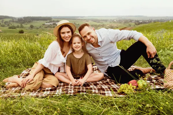 Bağlanma kavramı. Neşeli aile dışarıda pikniğin tadını çıkarıyor, battaniyeye oturup kameraya bakıyor, boş alan arıyor.