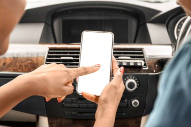 Genç siyahi bir adam ve kadın lüks bir arabada cep telefonu kullanıyor. Haftasonu gideceği yeri seçiyor. Akıllı telefondan takip uygulaması kullanıyor. Seyahat, tatil, yolculuk, seyahat konsepti