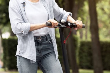 Parkta elektrikli scooter kullanan genç, güzel bir kız, kesilmiş, kopyalama alanı