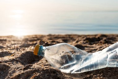 Tek kullanımlık plastik şişe çöpü dışarıda plajda yatarak kirleniyor. Kirlenmiş Sahil Çizgisi Konsepti. Boş Alan