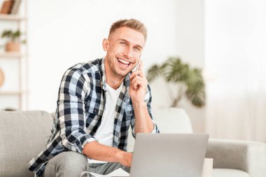 Kurumsal İletişim Konsepti. Neşeli adam telefon ediyor, dizüstü bilgisayarda yazı yazıyor ve başka yere bakıyor.