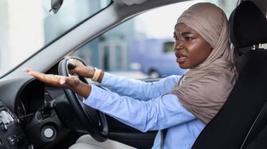 Stresli siyahi Müslüman kadın araba sürerken biriyle tartışıyor, ön koltukta oturuyor ve duygusal olarak jest yapıyor, trafik sıkışıklığında sıkışmış kızgın kadın, trafik kazası geçiriyor, kötü sürücülere şikayet ediyor.