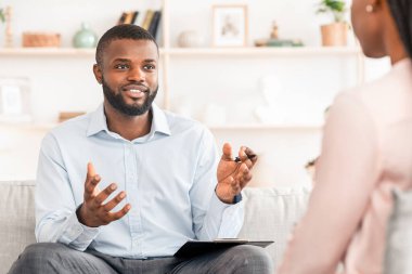 Evlilik terapisi. Siyahi adam profesyonel psikolog. Ofisinde buluşan evli çifte danışmanlık yapıyor. Aile uzlaşması için tavsiyelerde bulunuyor.