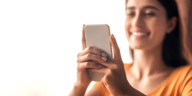 Sosyal medya bağımlılığı kavramı. Modern akıllı telefon, gülümseyen Arap kadın elleri, boş uzay. Cep telefonu tutan, arkadaşlarıyla sohbet eden ya da yeni flört uygulaması kullanan mutlu genç bayan.