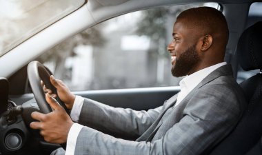 Neşe dolu Afrikalı Amerikalı genç şoför yola bakıyor ve gülümsüyor, mekanı kopyalıyor. Takım elbiseli mutlu siyah işadamı, başarılı bir iş gününden sonra evine dönüyor.