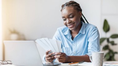 Genç siyahi kadın tasarımcı renk örneklerine bakıyor, yaratıcı ofiste masa başında çalışıyor.