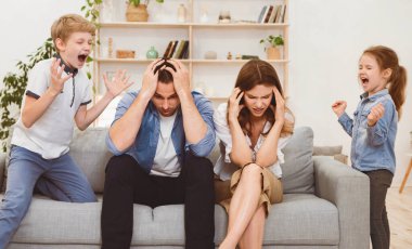 Yaramaz Çocuklar. Kontrol edilemeyen Çocuklar Evde Umutsuz Ebeveynlerin Yakınında Durarak Bağırıyor.