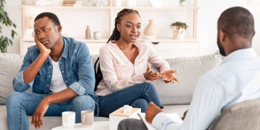 Duygusal Afrikalı bir adam, çift terapisinde eşiyle yaşadığı aile sorunlarından yakınıyor, ilgisiz eşinin yanında oturuyor.