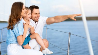 Aile Yatta Yelken Açtı. Veliler ve kızı tekne güvertesinde dikilip manzaralara bakıyor ve yaz tatilini deniz kenarında geçirmenin keyfini çıkarıyorlar. Yan Görünüm Görüntüsü