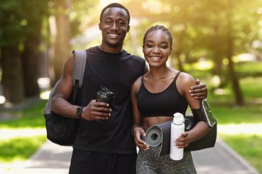 Spor kıyafetleri içinde uygun bir çift parkta antrenman yaptıktan sonra birbirlerine poz veriyorlar, kameraya sarılıyorlar ve gülümsüyorlar, sağlıklı yaşam tarzlarının tadını çıkarıyorlar, boş alanların tadını çıkarıyorlar.