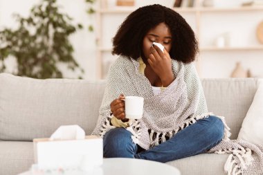 Grip belirtileri. Hasta siyah kız burnunu mendile sümkürdü. Kanepede oturup sıcak çay içti.