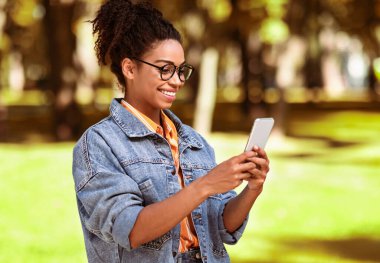 Neşeli Afrikalı Milenyum Kızı Şehir Parkı 'nda Telefon Kullanıyor. Mobil Uygulama Konsepti