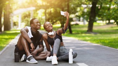 Sportif, neşeli bir Afrikalı çift parkta antrenmandan sonra Selfie çekiyor, dışarıda poz veriyorlar. Boş Alan