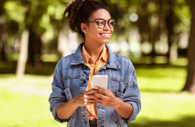 Mobil Uygulama. Hafta sonu parkta cep telefonu kullanan Afrikalı Öğrenci Kız.