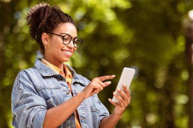 Güzel Afrikalı Kız Cep Telefonu Kullanıyor Dışarıdaki Park 'ta İnternet Gezintisi Yapıyor. Mobil Uygulama Kavramı. Boş Alan