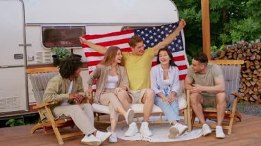 Bir grup farklı arkadaş hafta sonu kamp gezisi sırasında dışarıda dinlenir. Bir karavanın önünde Amerikan bayrağıyla poz verirken aynı kahkahaları ve güzel zamanları paylaşıyorlar..