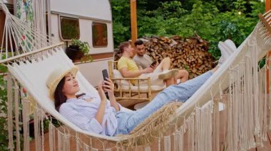 Bir grup farklı arkadaş yaz boyunca doğal ortamda dinlenirken, bir kişi hamakta telefonla konuşurken diğerleri de hafif sohbetler yaparak neşeli bir atmosfer yaratıyor..