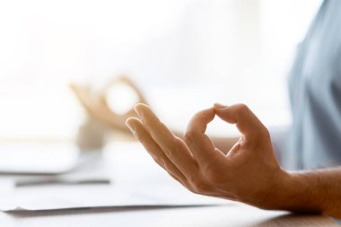 Zen. Ofiste çalışırken tanınamayan bir adamın meditasyon yaparken yakın plan çekimi, erkek çalışanın iş stresiyle başa çıkması, musra jesti yapması, seçici odaklı kırpılmış görüntü ve kopyalama alanı.