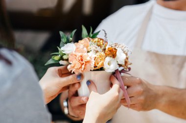 Fabrika dekorasyonu ve satışı için modern bir buket. Önlüklü ve koruyucu maskeli dost canlısı bin yıllık erkek satıcı müşteriye düzen veriyor. Çiçekçide kompozisyon seçici, bulanık...