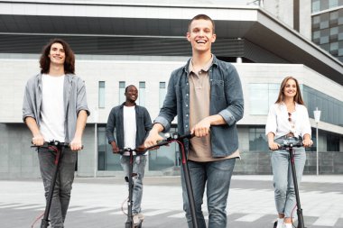 Kişisel Hareket Aygıtı. Tam uzunlukta beş gülen arkadaş kentsel alanda elektrikli scooter kullanıyor.