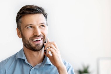 Neşeli erkek girişimci cep telefonuyla konuşuyor ve ofiste kahve içiyor, iş yerinde dinleniyor, hoş sohbetin tadını çıkarıyor, yakışıklı milenyum çalışanının işte mola vermesi, boş alan.