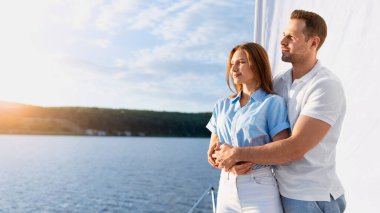 Yat Yelkenlisi Gemisi. Sevgi dolu bir çift, yelkenli gezintisinde ayakta durup, güvertede sarılıp açık denizde gün batımını seyrediyor. Deniz kenarında yaz tatili konsepti. Metin için Boş Alan