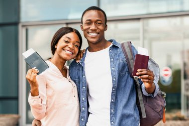 Tatile hazırım. Ellerinde pasaportlarıyla havalimanı yakınlarında poz veren heyecanlı siyah eşler, kameraya gülümseyen, boş alan