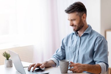 İçişleri Bakanlığı. Gülümseyen Freelancer Laptop 'ta e-postaları kontrol ediyor, kahve içiyor, uzaktan çalışmanın keyfini çıkarıyor, Boşluğu kopyalıyor.