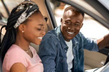 Heyecanlı Afro-Amerikan çift gezginleri rahat araba, yan görüş, kopyalama alanı kullanırken haritaya bakıyorlar. Mutlu milenyum siyahi erkek ve kadınları, seyahate başlamadan önce haritayı kontrol ediyor, arabada oturuyor.