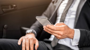 Arabadaki arka koltukta oturan, akıllı telefon kullanan, e-posta ve fotokopi alanını kontrol eden bir yönetici. Tanımlanamayan işadamı toplantıya gidiyor, ofise giden bir yol üzerinde çalışıyor, cep telefonu kullanıyor.