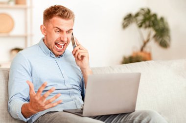 Sinirli adam cep telefonuyla konuşuyor, bağırıyor, kanepeye oturuyor, dizüstü bilgisayar kullanıyor, boşluğu kopyalıyor.