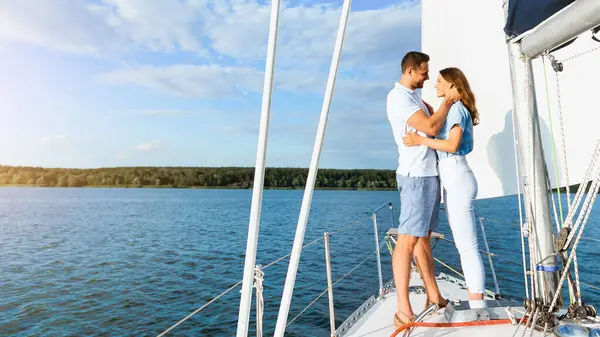 Yattaki çift, deniz kenarında yelkenli teknesinde sarılıp romantik yaz tatilinin tadını çıkarıyor. Dikey, Boş Alan