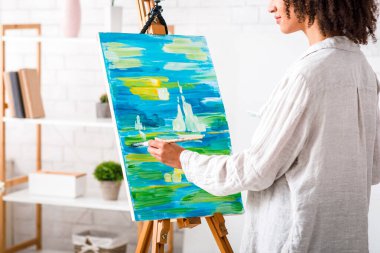 Öğretmenden online çizim dersi. Afrikalı Amerikalı bir kadın bir resim çiziyor ve öğrencilere oturma odasının iç kısımlarında serbest alan dersi veriyor.