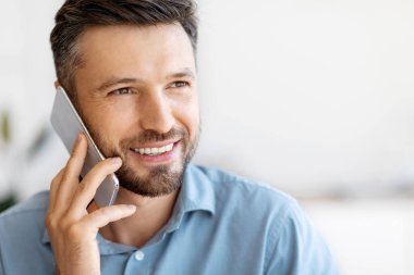 Telefon var. Cep telefonuyla konuşan yakışıklı adamın yakın plan çekimi, mobil iletişimin tadını çıkarmak, hoş sohbetler yapmak, başka yere bakmak, gülümsemek, seçici odaklanma, kopyalamak...