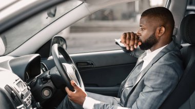 Düşünceli Afro-Amerikan genç iş adamı pahalı araba kullanıyor, sabah ofise gidiyor. Takım elbiseli sinirli genç bir adamın yüzüne dokunması, işiyle ilgili sorunları olması...
