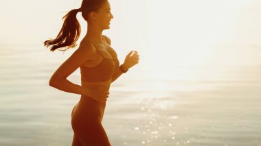 Sabah deniz kenarında koşan gülümseyen kadının yan görüntüsü, boşluğu kopyalamak.