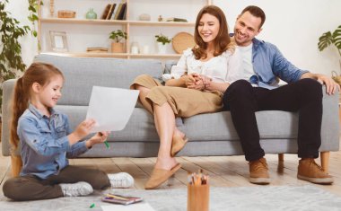 Aile Hafta Sonu. Ebeveynler kızlarına bakıyor. Evde birlikte oturarak rahatlıyorlar. Seçici Odaklanma