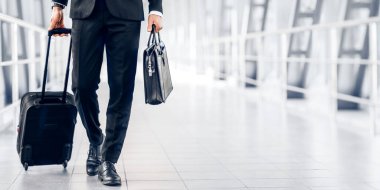 Tanımlanamayan siyah takım elbiseli girişimci havaalanı terminalinden geçiyor, bavul ve çanta taşıyor, kopyalama alanı var. Çantası ve çantası olan zengin işadamı iş gezisine gidiyor.