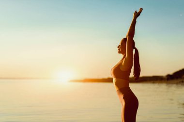 Sağlık Konsepti. Sakin, zinde bir kadın kollarını uzatıyor. Sabahları kıyıda duruyor. Kopya uzayı.