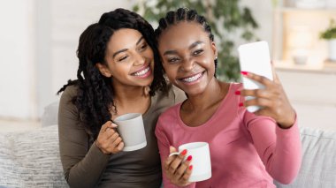 Neşeli Afrikalı kankalar evde çay içerken selfie çekiyorlar.